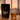 A bag of Nightfall herbal tea beside a steaming glass mug at dusk, with a soft-focus Mediterranean-style window and sunset in the background